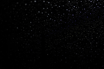 Many white drops in bokeh on a black background