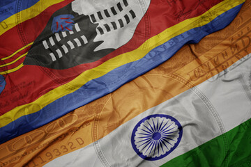 waving colorful flag of india and national flag of eswatini on the dollar money background. finance...