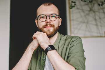 Portrait of bearded hipster guy dressed in casual wear looking at camera while enjoying recreation time in modern cafeteria with tasty coffee drink.Handsome young man in eyeglasses resting in cafe