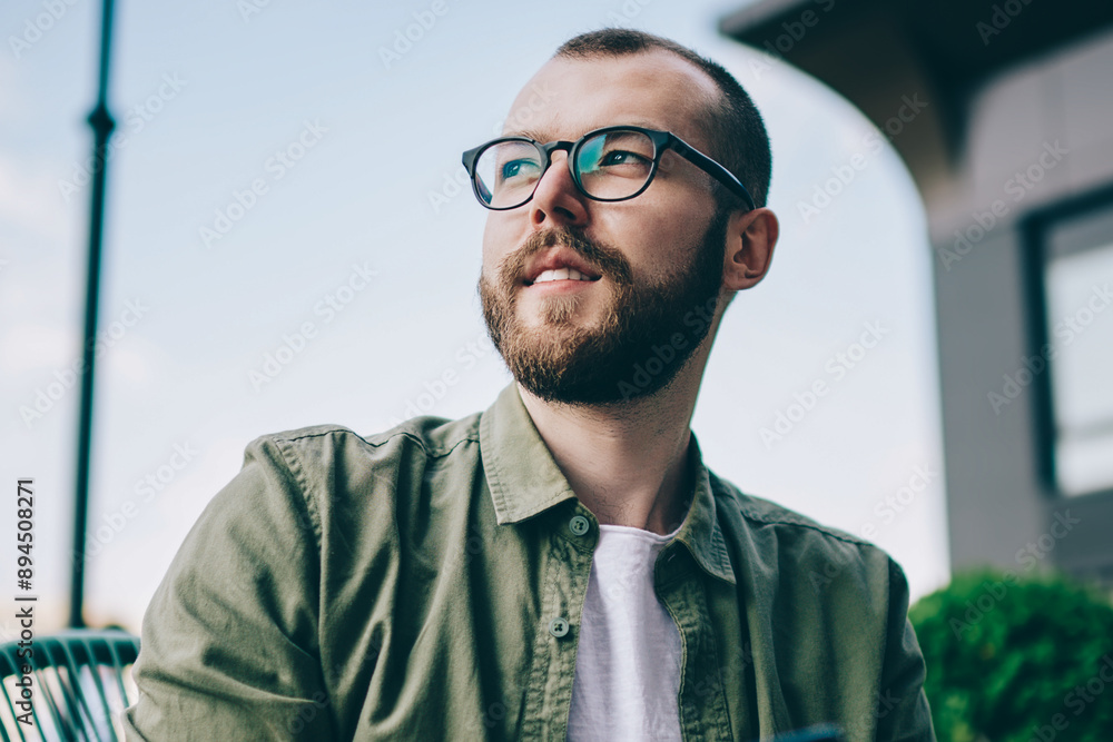 Poster pondering bearded young man looking away while thinking on idea for publication in blog on smartphon