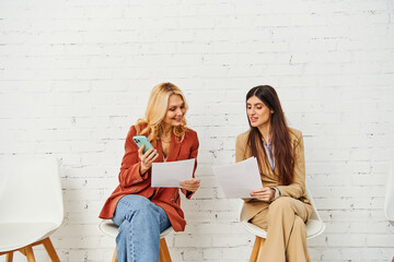 Two women seated, engrossed in papers.
