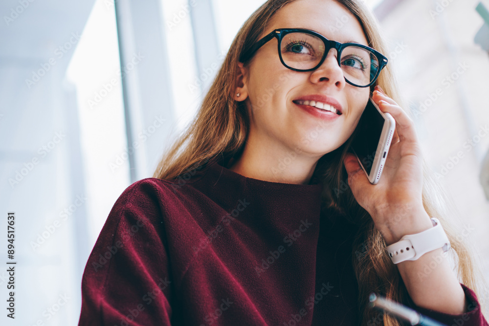 Poster positive hipster girl calling to customer service using application on mobile phone while sitting at