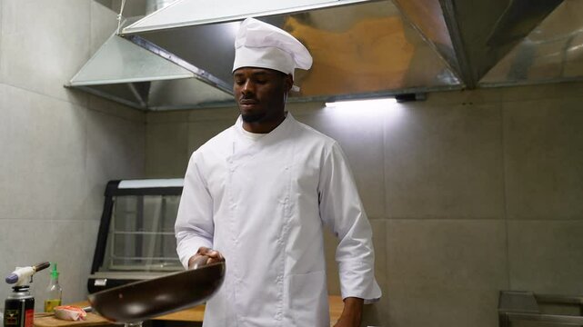 African American chef cook food with fire at kitchen restaurant. Cook with wok at kitchen