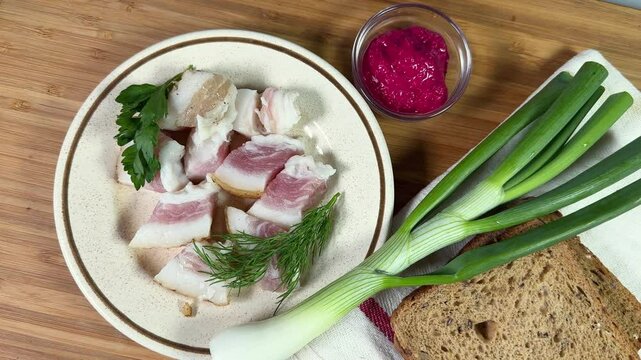 Salted pork fatback slices, bread and seasonings on cutting board