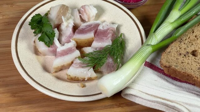 Salted pork fatback slices, bread and seasonings on cutting board