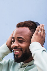 Obraz premium Young black man in hoodie listening music with headphones