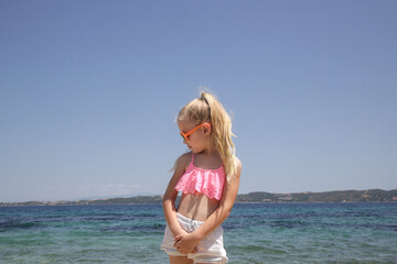 Portrait of 7 years old fashionable girl in pink crop top, orange sunglasses and long blonde hair...