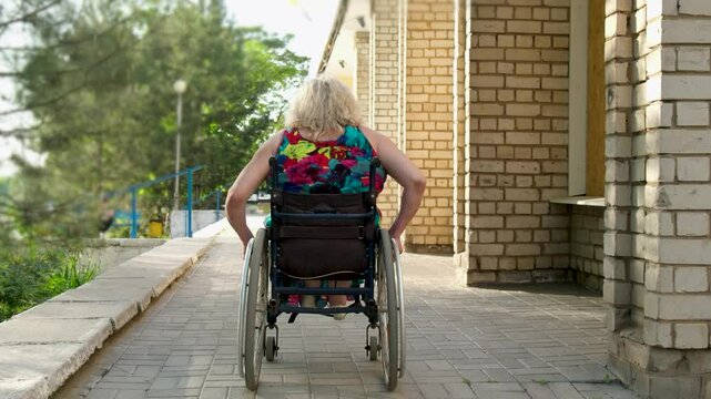 Disabled white woman in a wheelchair on the street. Outdoor walk of woman in wheelchair