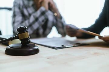 In a lawyer's office, a businessman consults an attorney for legal advice on a contract. The gavel symbolizes authority and justice. The lawyer explains the legislation and provides guidance on the ag