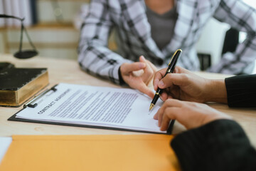 In a lawyer's office, a businessman consults an attorney for legal advice on a contract. The gavel symbolizes authority and justice. The lawyer explains the legislation and provides guidance on the ag