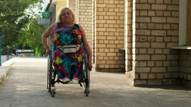 Disabled white woman in a wheelchair on the street. Outdoor walk of woman in wheelchair