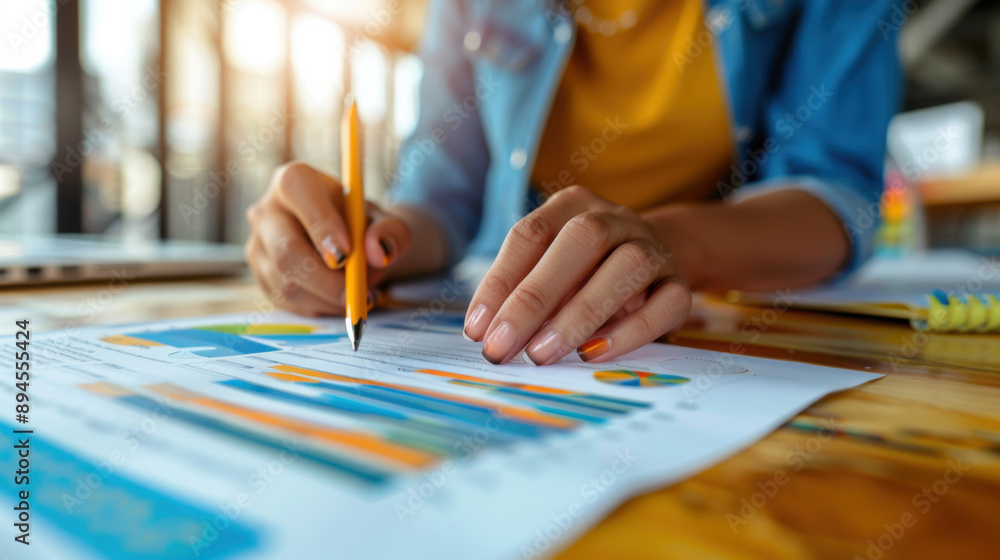 Poster close-up of a person analyzing financial charts with a pencil, focusing on data and business strateg