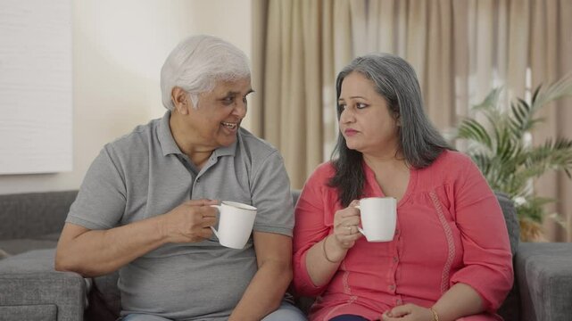 Happy Indian old couple drinking tea and talking