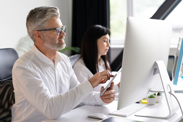 Professional Office Environment With Focused Colleagues Working Together On Computer And Tablet
