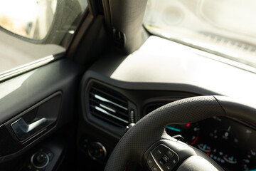 The interior of a car with a leather steering wheel and air vents