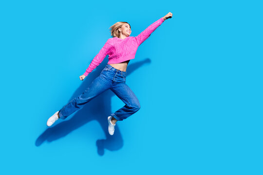 Full body portrait of nice young woman jump fly empty space wear sweater isolated on blue color background