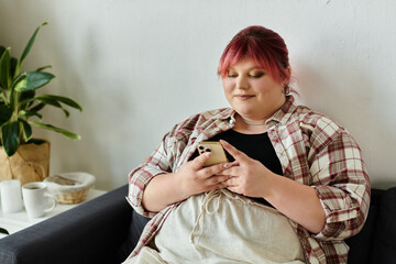 A woman in a plaid shirt relaxes on a couch while scrolling on her phone.