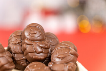 Chocolates in the shape of Christmas figures in the wooden box on the red background