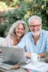 A couple of 60-year-olds sitting in front of a laptop. AI generative.