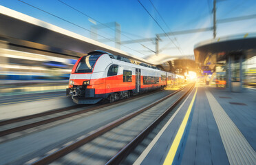 High-speed passenger train moving at railway station at sunset