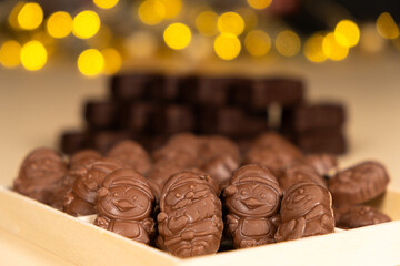 Chocolates in the shape of Christmas figures on the background of a flashing garland