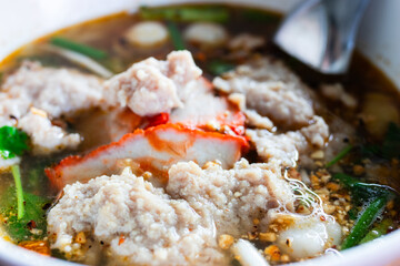 Tom Yum Noodles with minced pork and red pork, topped with peanuts. Thai style food.