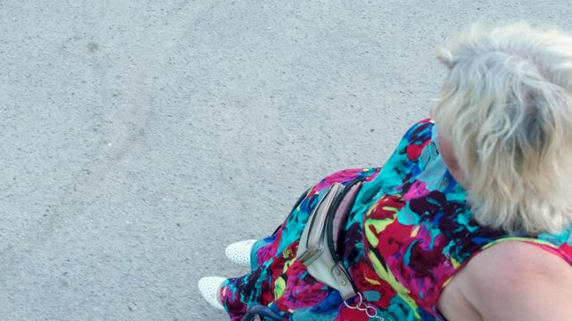 Disabled white woman in a wheelchair on the street. Outdoor walk of woman in wheelchair