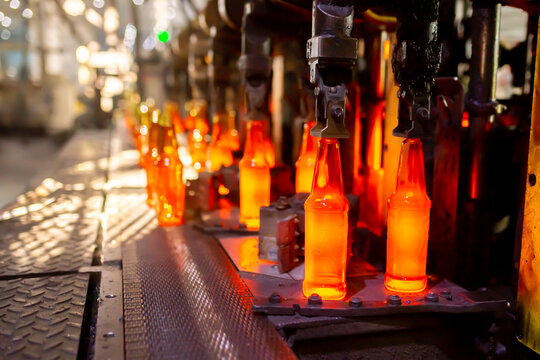 Glass factory, production of glass containers. Molten glass is blown into molds. Robotics in industry. Modern technologies, robotic machines produce products. Technological work at the plant.