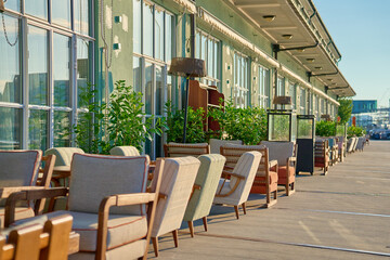 Street cafe in morning. Empty outdoor patio with chairs and potted plants on table. Terrace with tables waiting for visitors in European city