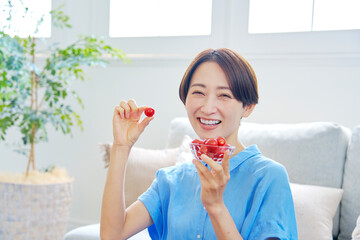 自宅でミニトマトを食べる女性　カメラ目線
