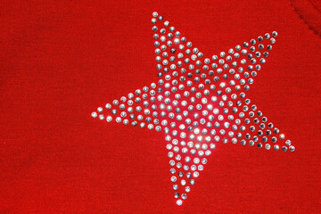 Red knitted fabric with rhinestones laid out in the shape of a star. Texture of red knitted fabric with rhinestones