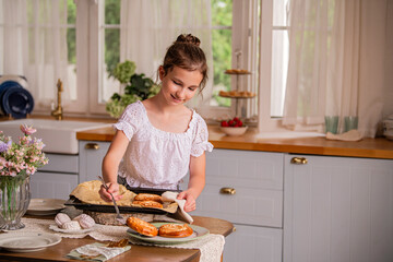 girl holding a baking tray with freshly baked pies in her hands in the interior of a country house kitchen.