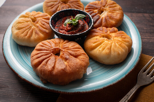 Meat open pies, belyashi on a turquoise plate with tomato sauce and basil. A traditional Tatar dish.