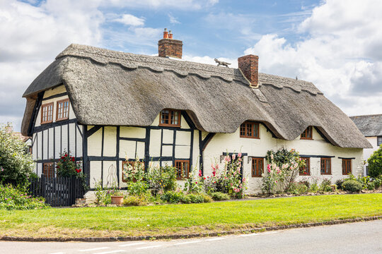 traditional english village black and white thatched cottage Cotswolds UK