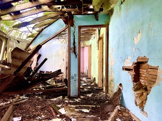 Interior of a destroyed bedroom in an abandoned house in rural North Dakota with a collapsed roof and damaged wall. © Andrew