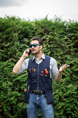 Fototapeta premium Portrait of handsome handyman in uniform with tools standing outdoors