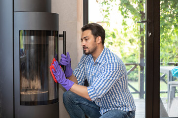A young man cleans a fireplace to be prepared for the harsh winter during an energy crisis