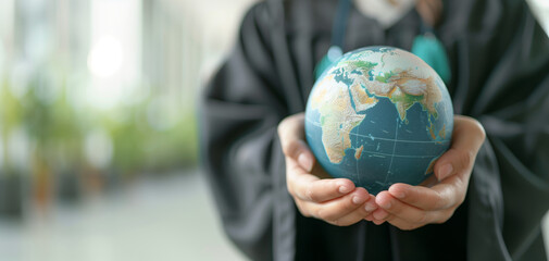 A graduate holds a globe, symbolizing knowledge, global awareness, and the future of education and environmental responsibility.