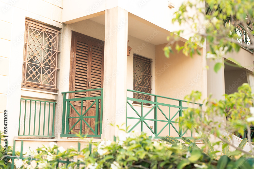 Aufkleber a view of a balcony with wooden shutters and green railings partially obscured by foliage