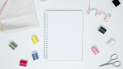 Composition with various threads and sewing accessories on white background. Mock up notebook