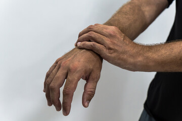 Fototapeta premium Close up of a man suffering from inflammation, massaging his wrist over white background. By repetitive movements. Work-related pathologies