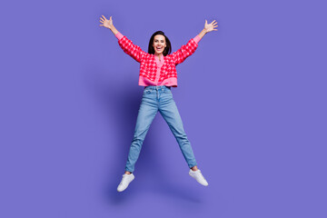 Full length photo of adorable lovely girl wear pink cardigan jumping high empty space isolated purple color background