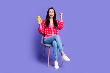 Full length photo of lucky lovely girl wear pink cardigan winning game modern gadget empty space isolated purple color background