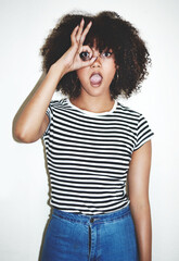 Portrait, girl and hand binoculars with shocked, white background and fashion for style or trendy clothes. Female person, gesture and expression as surprised, curious or playful in studio backdrop