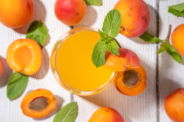 Apricot mojito or lemonade cold fruit drink, summer iced fruit juice non-alcohol mocktail with mint and lemon, on white wooden table
