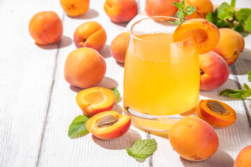 Apricot mojito or lemonade cold fruit drink, summer iced fruit juice non-alcohol mocktail with mint and lemon, on white wooden table
