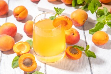 Apricot mojito or lemonade cold fruit drink, summer iced fruit juice non-alcohol mocktail with mint and lemon, on white wooden table
