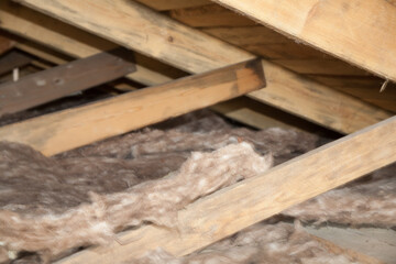 Construction worker mineral wool thermally insulating house attic with glass wool