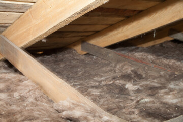 Construction worker mineral wool thermally insulating house attic with glass wool