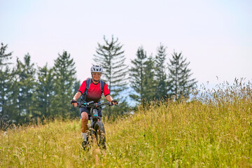 Fototapeta premium nice active senior woman riding her electric mountain bikeon Salmas summit in Oberstaufen, Allgaeu Alps , Bavaria, Germany 